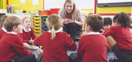 A group of children sitting in a circle in front of a teacher.